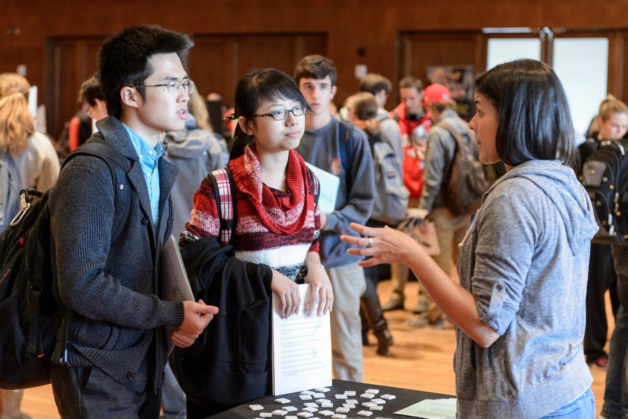 Staff member talks to two students at a majors fair